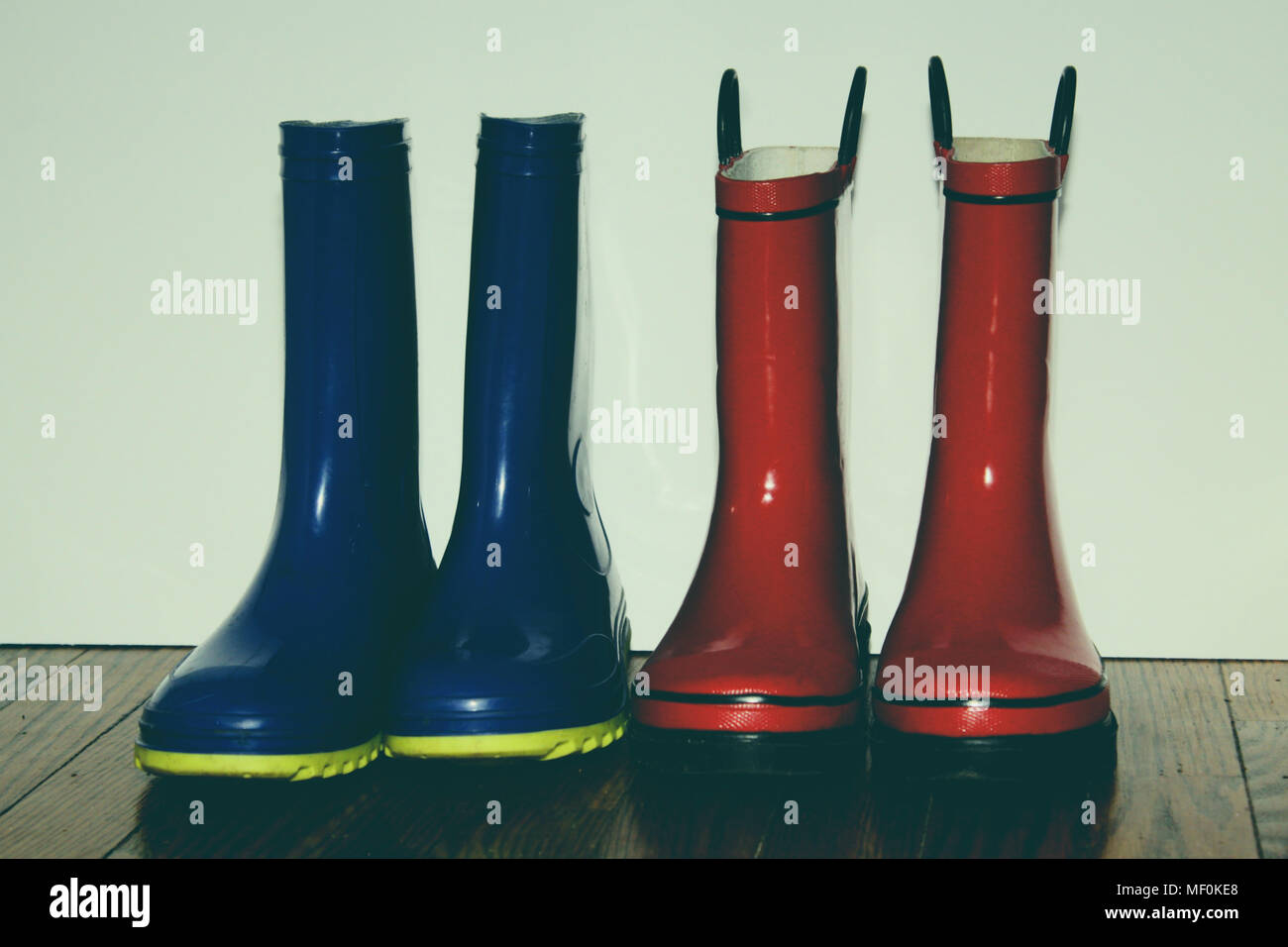 Zwei Paare der Kinder rainboots gegen die Wand auf einen Hartholzboden Stockfoto