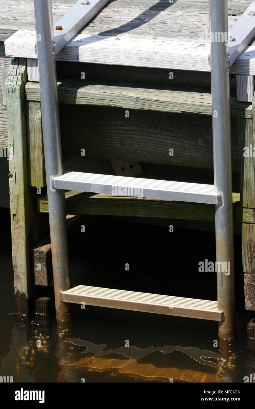 Eine Leiter mit 3 Sprossen mit Sitzen in Wasser und bis zum Ende der Pier befestigt Stockfoto