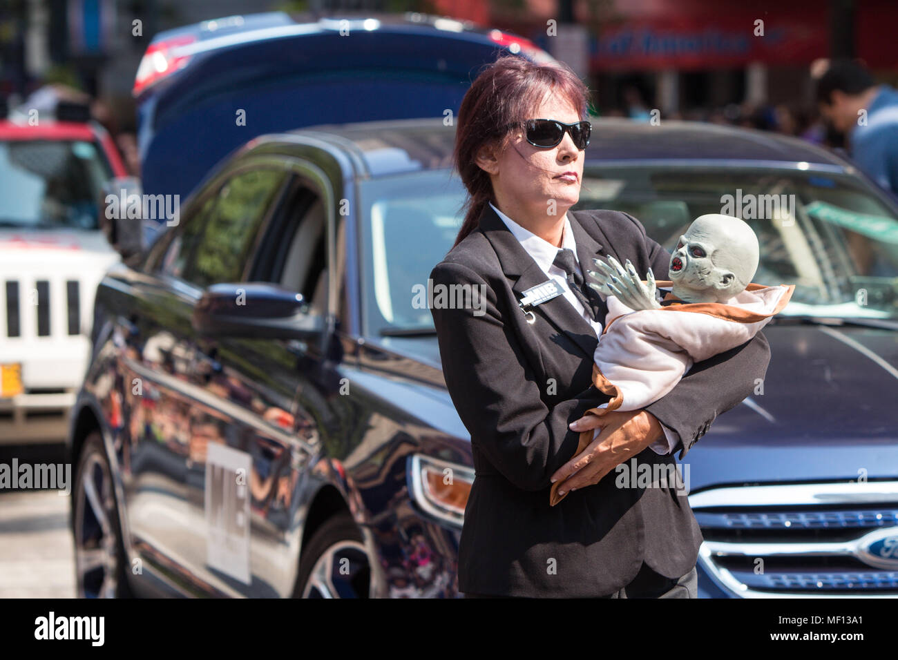 Eine Frau, gekleidet wie ein Men In Black Agent führt ein alien Baby beim Gehen in die jährliche Dragon Con Parade am 5. September 2015 in Atlanta, GA. Stockfoto