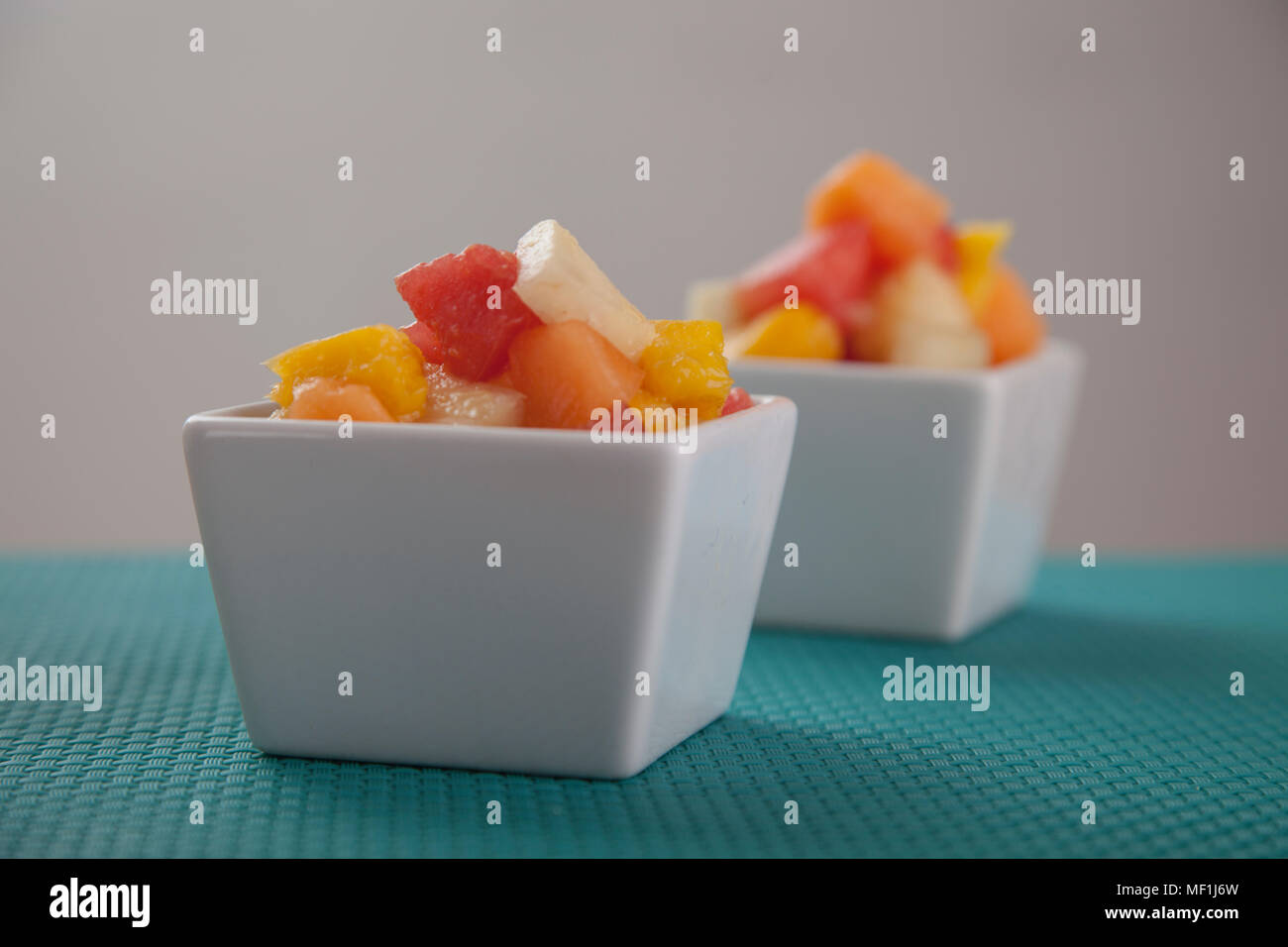 Obst Salat Mischung aus Melone, Banane, Melone, Orange und Ananas in einer kleinen Porzellan Schüssel, Frühstück oder gesunden Snack, Konzept der Gewichtsverlust Stockfoto