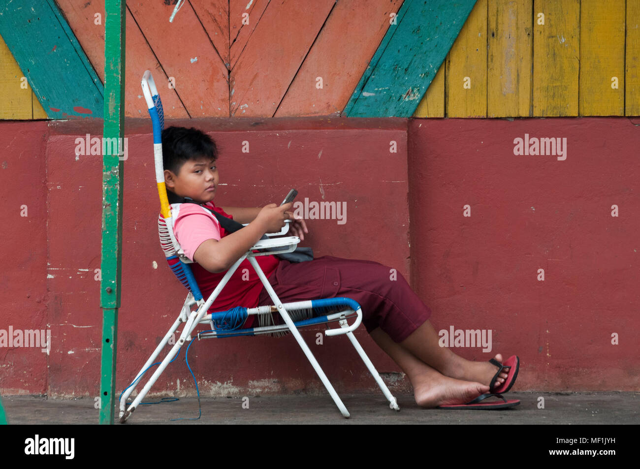 Junge entspannende außerhalb einer Halle auf dem Nachtmarkt, Kota Kinabalu, Sabah Stockfoto