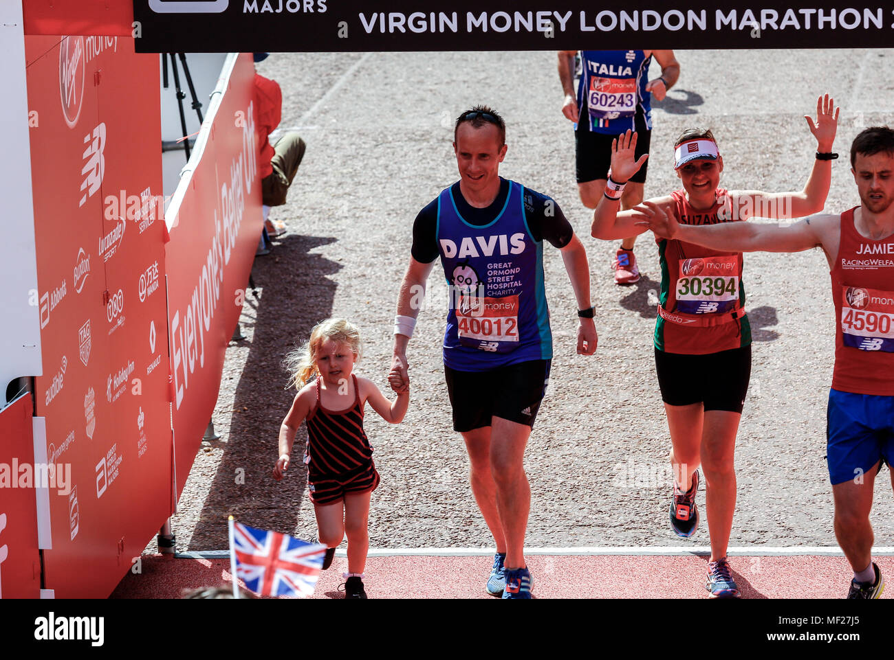 Läufer über die Ziellinie fährt mit einem kleinen Mädchen, das mit ihm während der Virgin Money London Marathon in London, England am 22. April 2018. Stockfoto