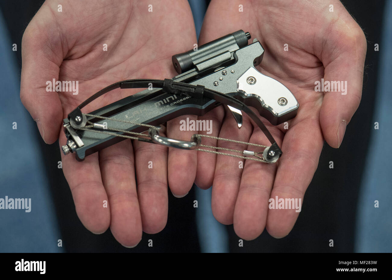 24 April 2018, Deutschland, Frankfurt/Main: Ein Offizier präsentiert eine  Miniatur Armbrust bei der jährlichen Pressekonferenz der Zollstelle. Das  Objekt, ursprünglich aus China, Zahnstocher und dünnes Metall Sticks über  eine Distanz von mehreren