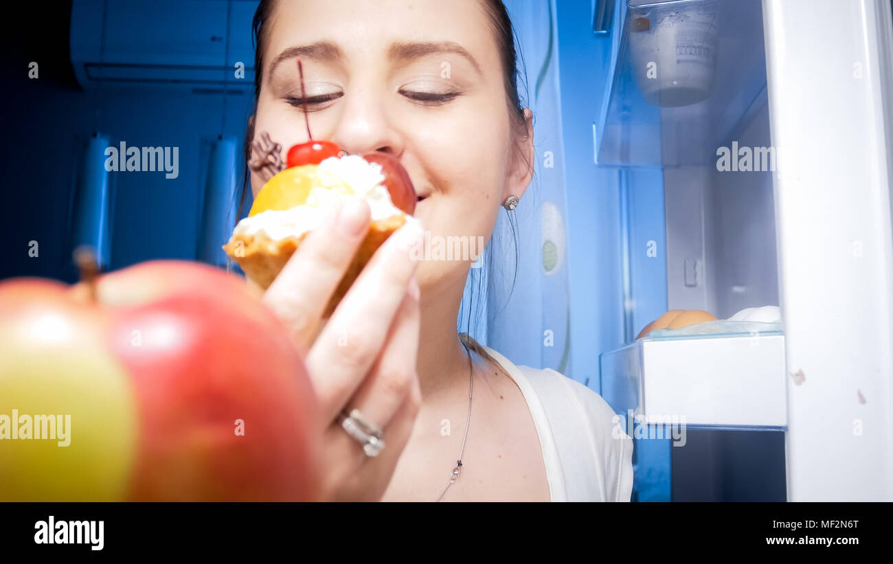Closeup Bild von der Innenseite der Kühlschrank der jungen Frau Kuchen essen bei Nacht Stockfoto