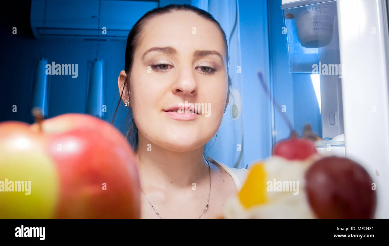 Closeup Portrait von der Innenseite der Kühlschrank bei Nacht der Frau auf der Suche nach Lebensmittel in den Regalen Stockfoto