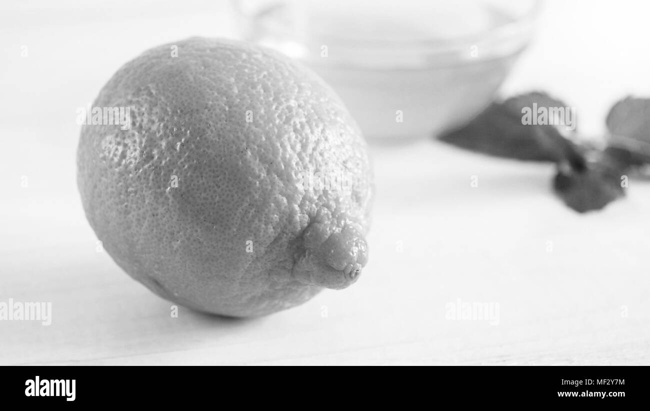 Detailansicht schwarz-weiß Bild von ganzen Frische Zitrone liegen auf hölzernen Schreibtisch Stockfoto