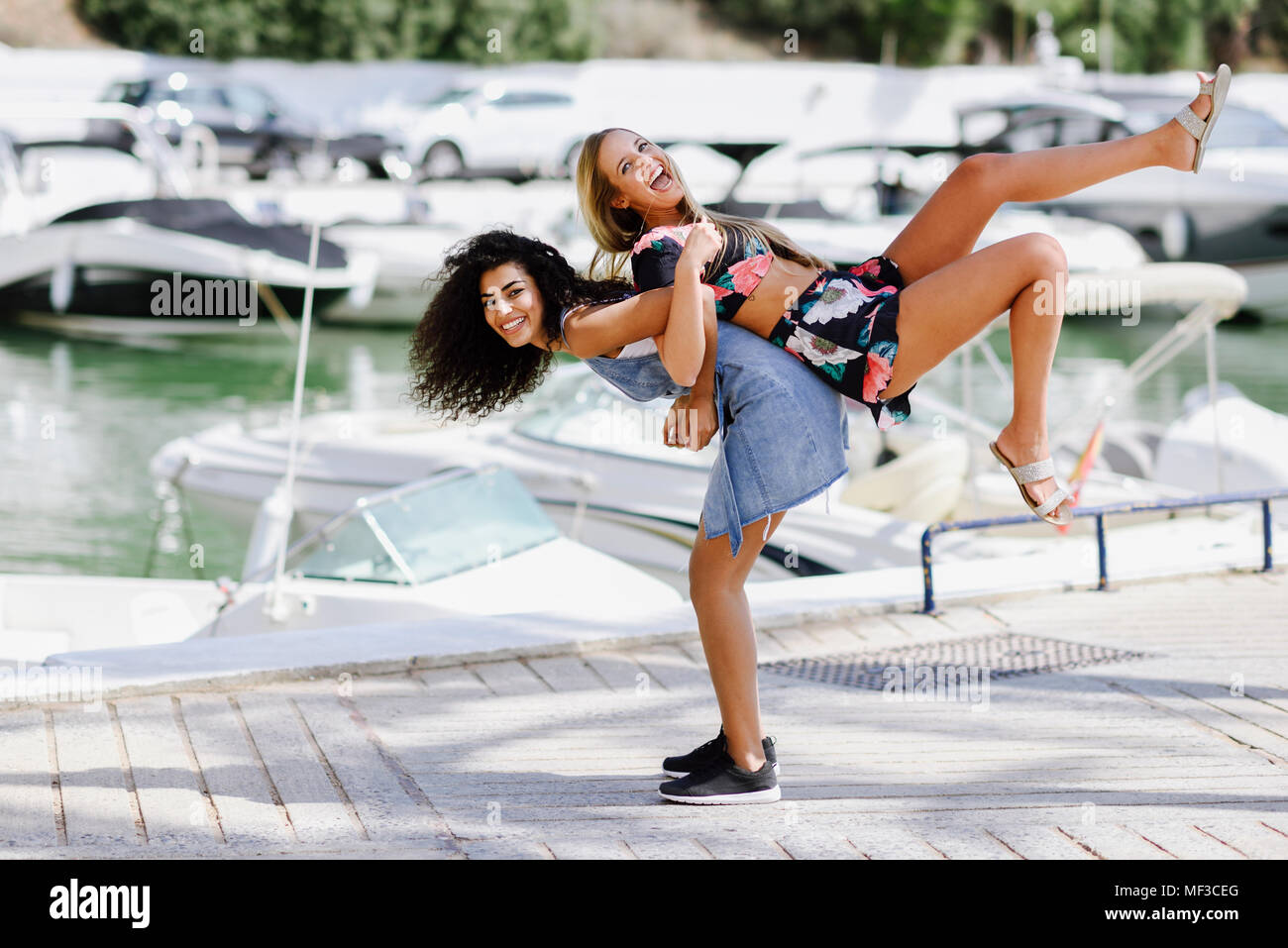 Spanien, Andalusien, Marbella. Zwei multirassischen Frauen Spaß zusammen mit im Boot Hafen. Lifestyle Konzept. Stockfoto