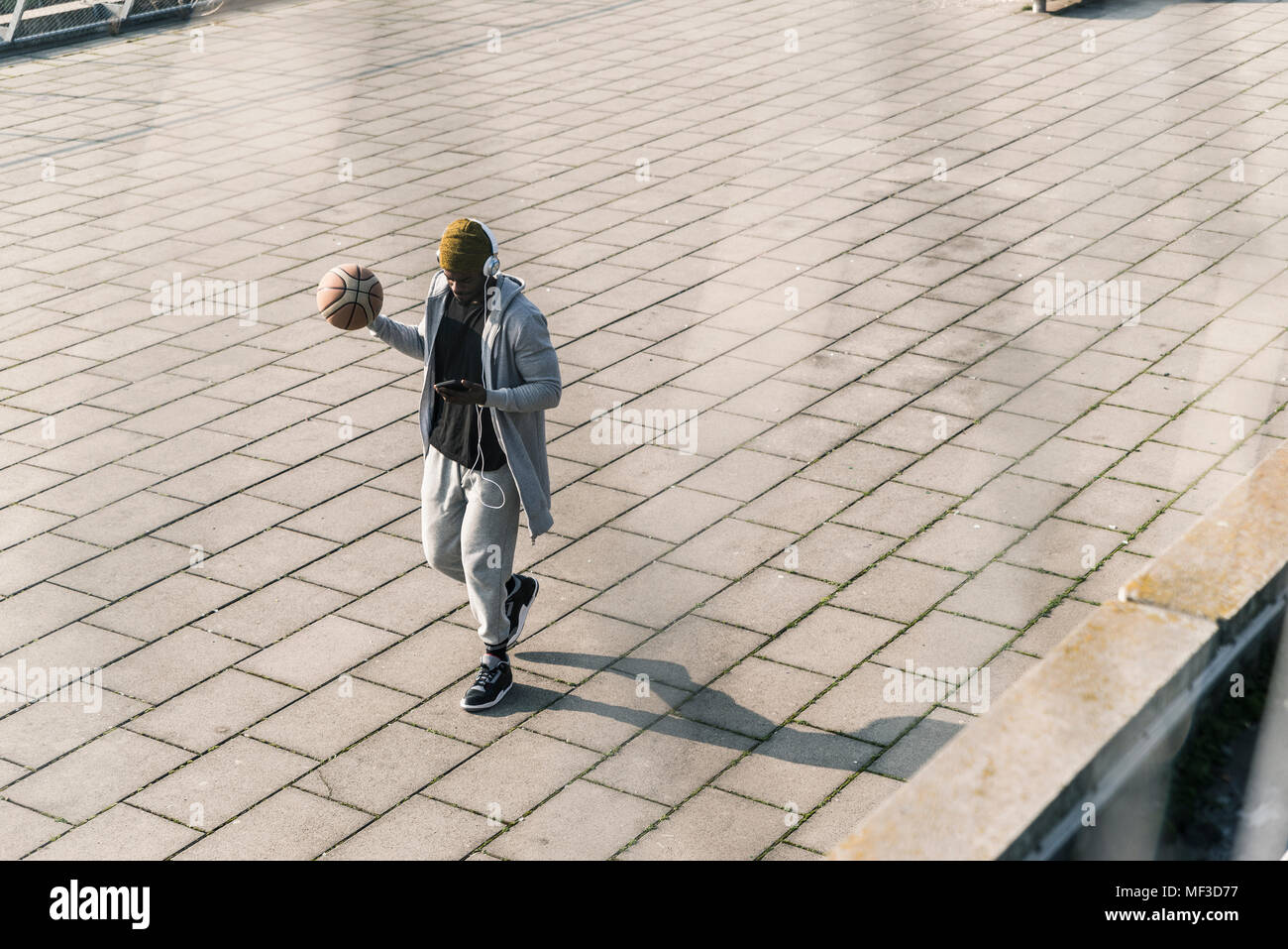 Junger Mann mit Basketball zu Fuß auf ein Quadrat Stockfoto
