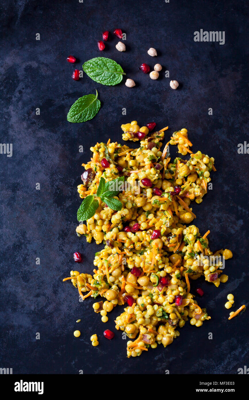 Couscous Salat mit Kichererbsen und Preiselbeeren auf dunklem Boden Stockfoto