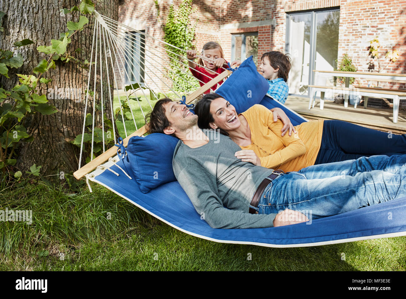 Happy Family spielen in der Hängematte im Garten ihres Hauses Stockfoto