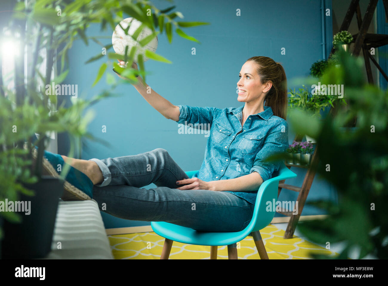 Schöne Frau in ihrem Haus sitzen, mit Pflanzen dekoriert, im Globe suchen Stockfoto