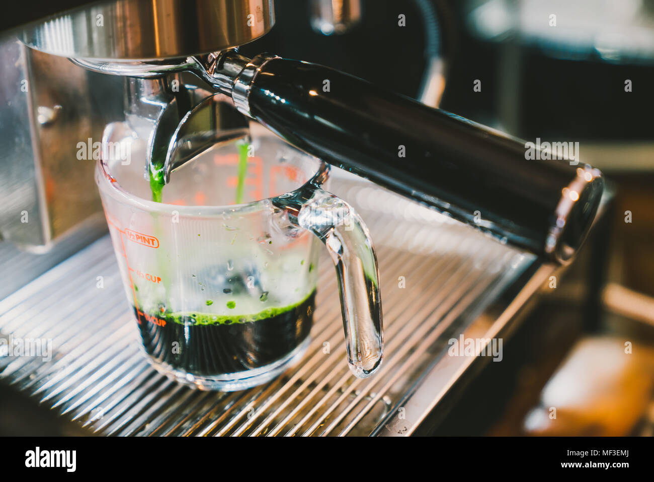 Barista heiße Grüner Tee mit Kaffeemaschine Maschine, close-up auf der Skala messen Glas. Cafe Lifestyle, Essen und Trinken Small Business Konzept Stockfoto