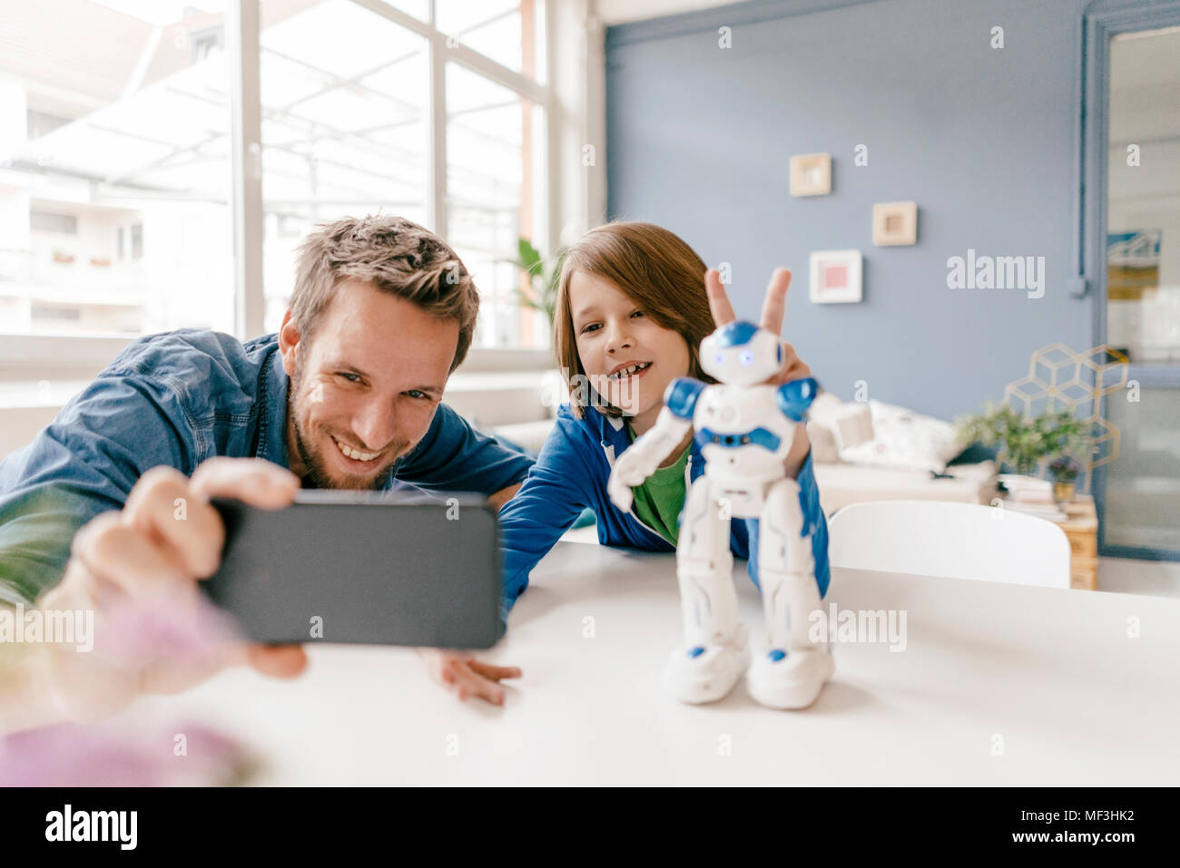 Gerne Vater und Sohn eine selfie mit Roboter auf dem Tisch zu Hause Stockfoto