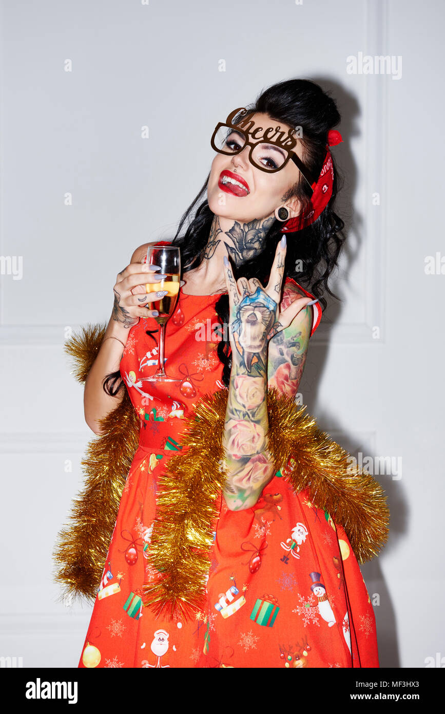 Portrait von tätowierten Frau mit Champagner Glas mit Rock und Roll Sign Stockfoto