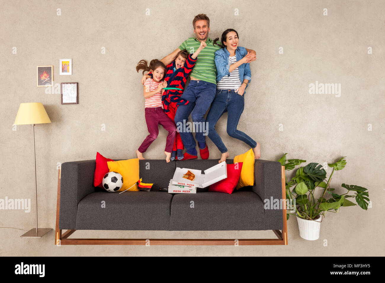 Glückliche Familie mit zwei Kindern, Fußball im Wohnzimmer Stockfoto