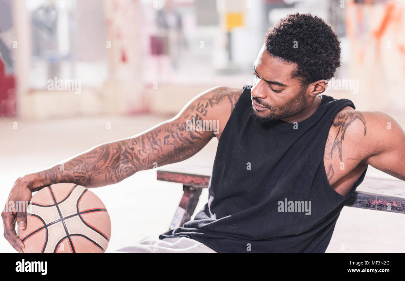 Menschen mit Tätowierungen sitzen Holding Basketball Stockfoto