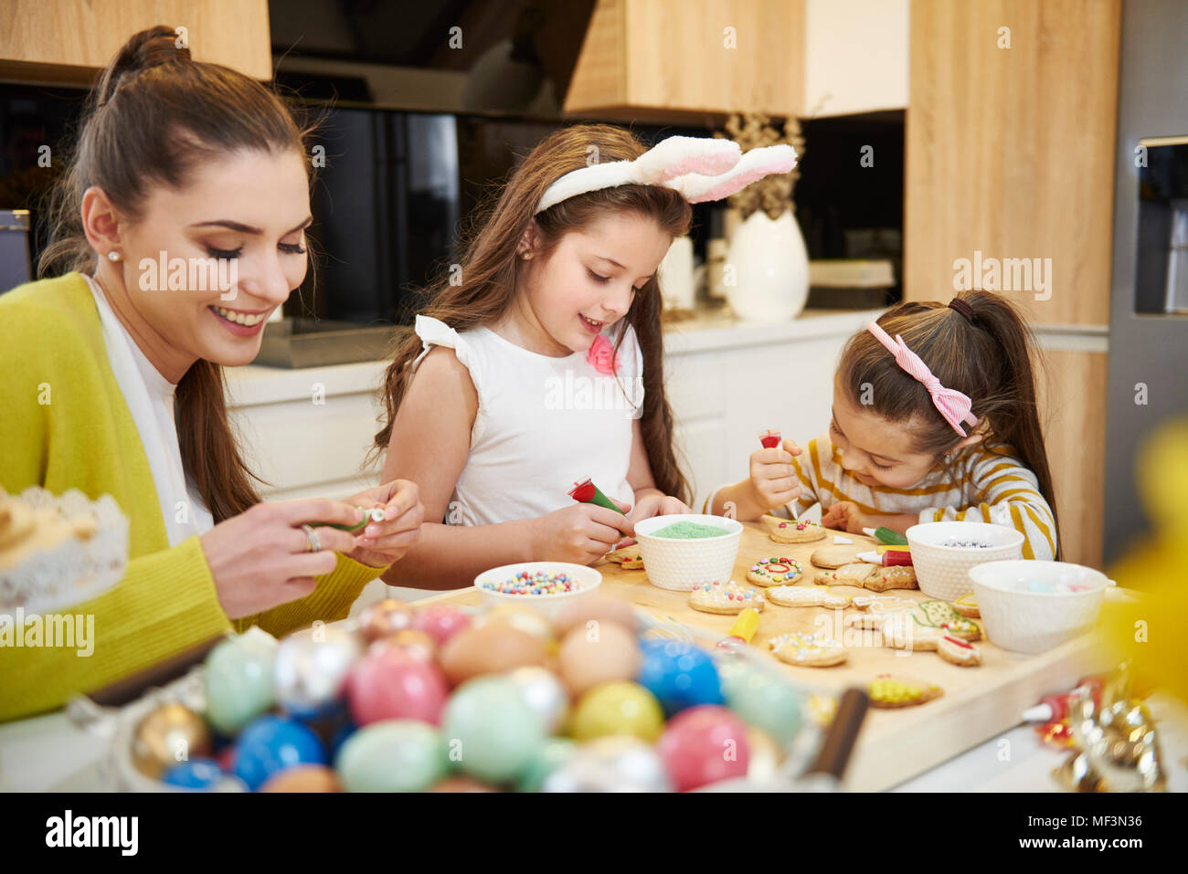 Mutter mit Töchtern Dekoration Ostern Cookies in der Küche Stockfoto