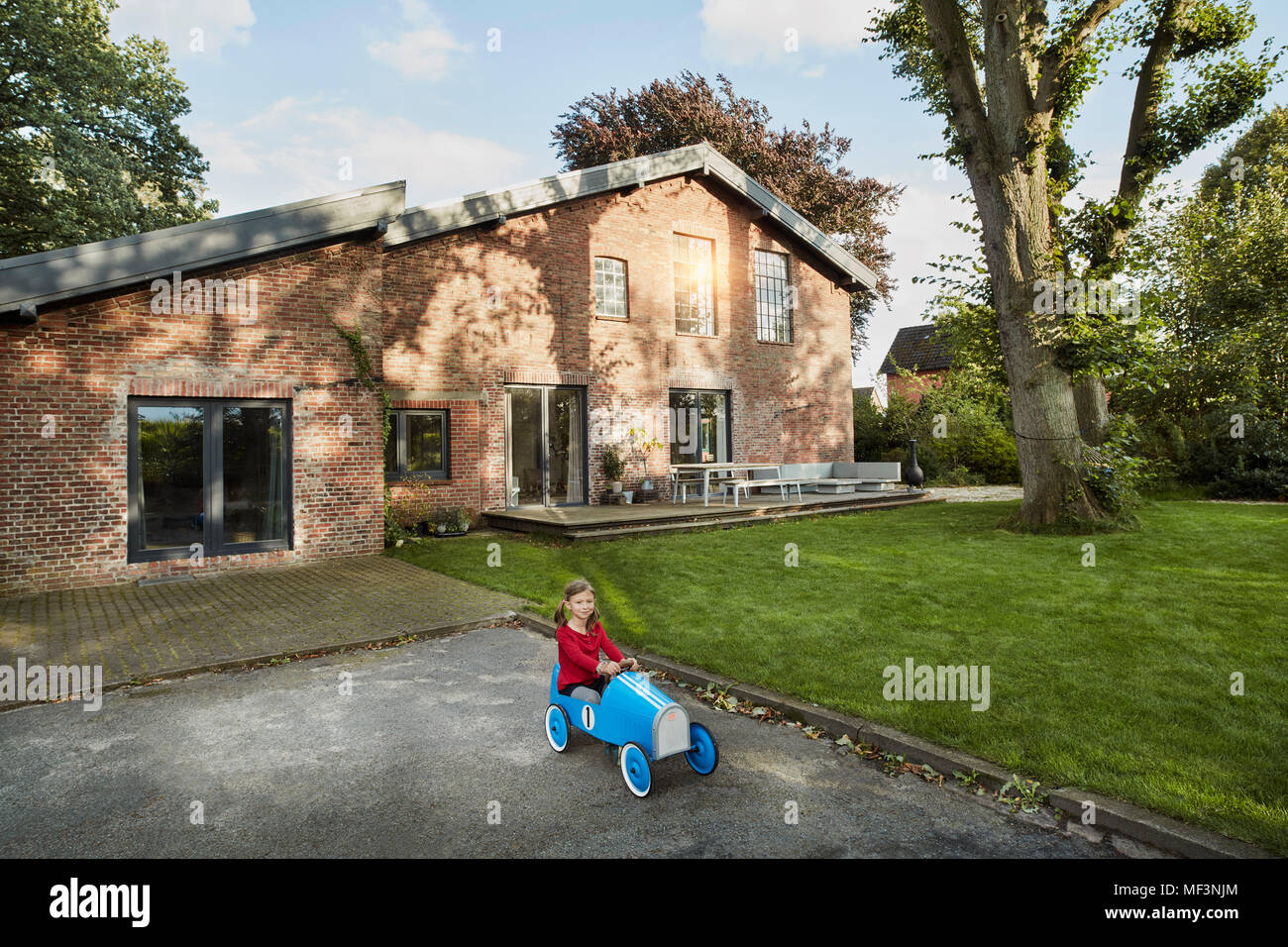 Mädchen spielen mit soapbox in der Einfahrt des Wohnhaus Stockfoto