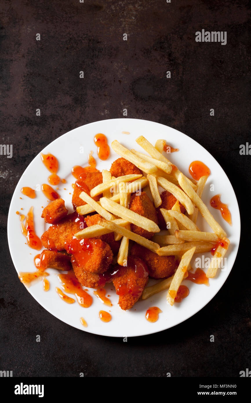 Platte von Chicken Nuggets mit Sweet Chili Sauce und Pommes Frites auf Dark Metal Stockfoto