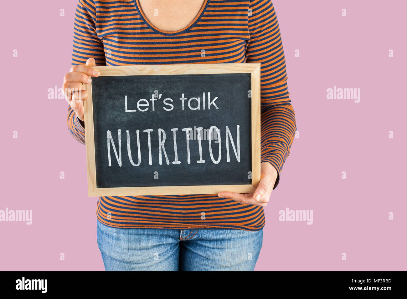 Weibliche Hände, die kleine Schwarze Schiefertafel vor dem Körper mit Text saying Let's talk Ernährung Stockfoto