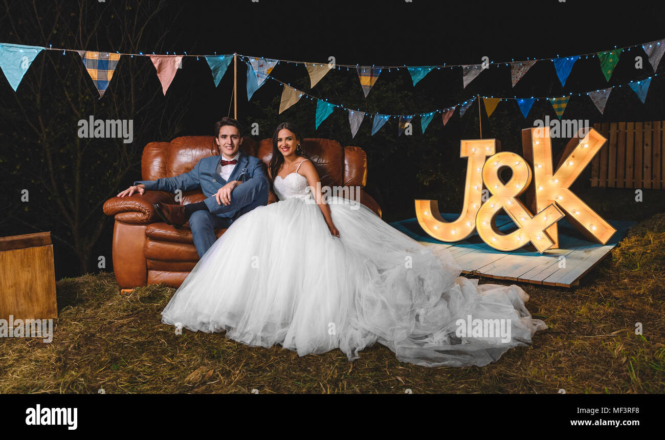 Portrait der glücklichen Hochzeit paar sitzt auf einem Sofa auf einer Nacht Feld Partei Stockfoto