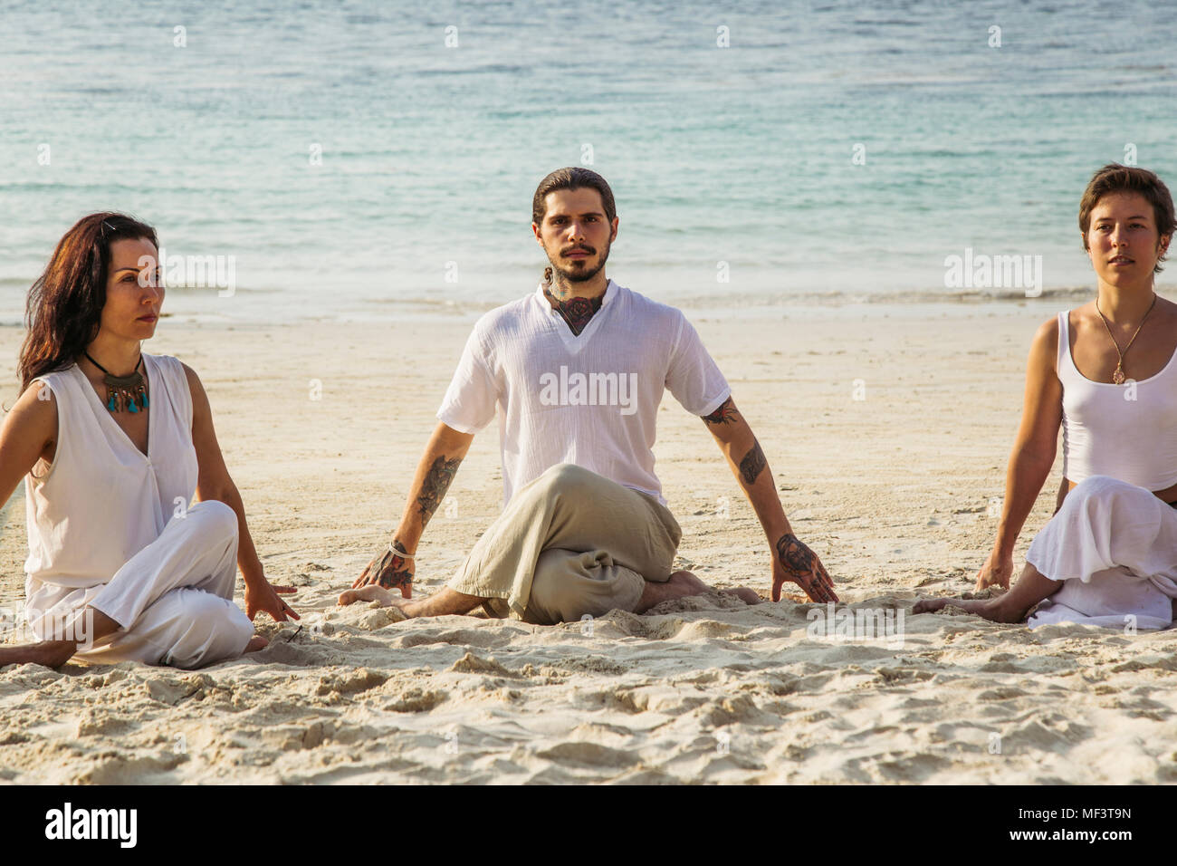 Thailand, Koh Phangan, drei Menschen, die Yoga am Strand Stockfoto