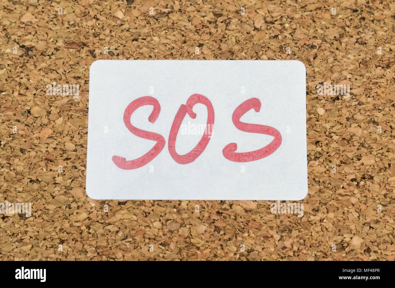 Wort SOS handschriftlich auf einem Aufkleber an eine Pinnwand angeheftet Stockfoto