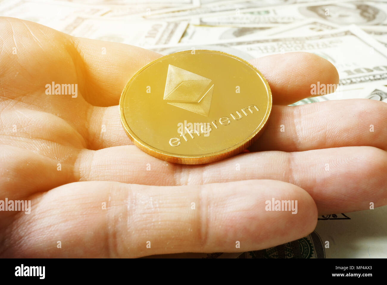 Hand Münze des Astraleums ETH unter Dollar Banknoten. Cryptocurrency Bergbau. Stockfoto