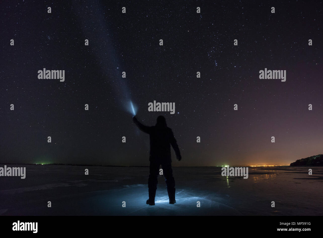 Russland, Amur Oblast, Silhouette der Mann mit Blue Ray auf gefrorenen Zeya Fluss in der Nacht unter Sternenhimmel Stockfoto