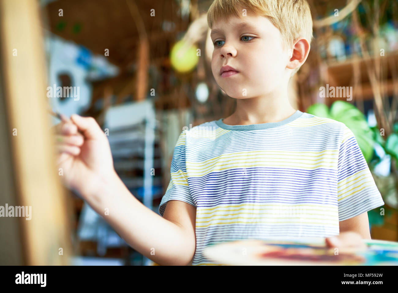 Talentierte junge Malerei auf Staffelei Stockfoto