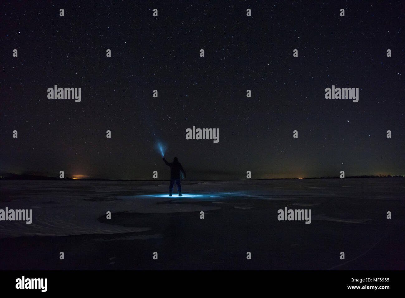 Russland, Amur Oblast, Silhouette der Mann mit Blue Ray auf gefrorenen Zeya Fluss in der Nacht unter Sternenhimmel Stockfoto