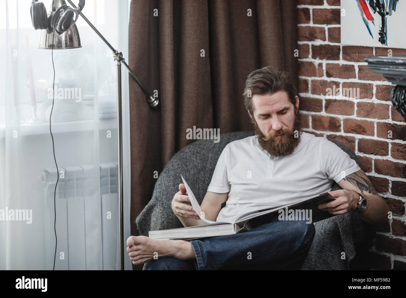 Mann sitzt auf Sessel bei Kaffee suchen - Buch Stockfoto