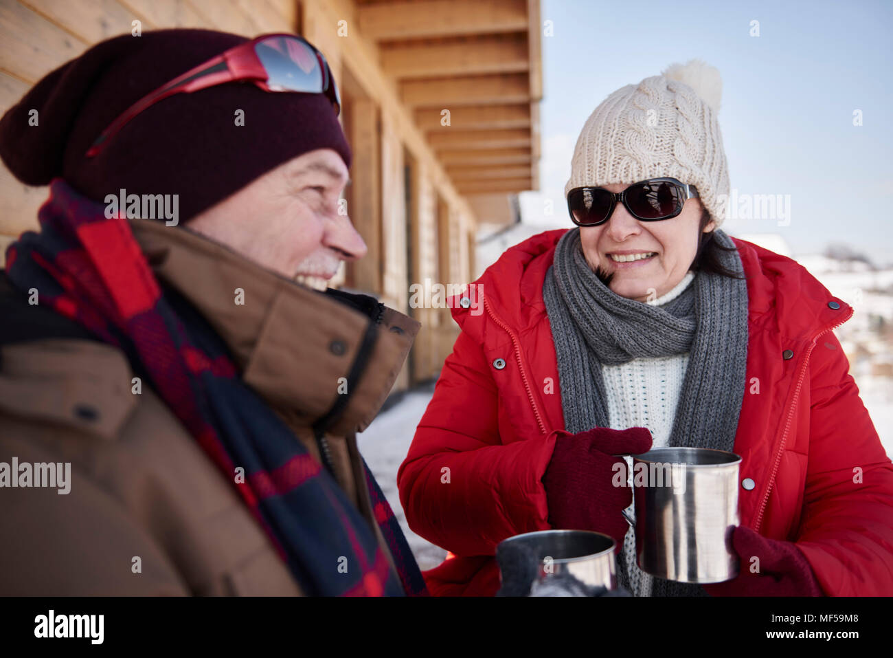 Glückliches junges Paar mit heißen Getränken im Freien an Hütte im Winter Stockfoto