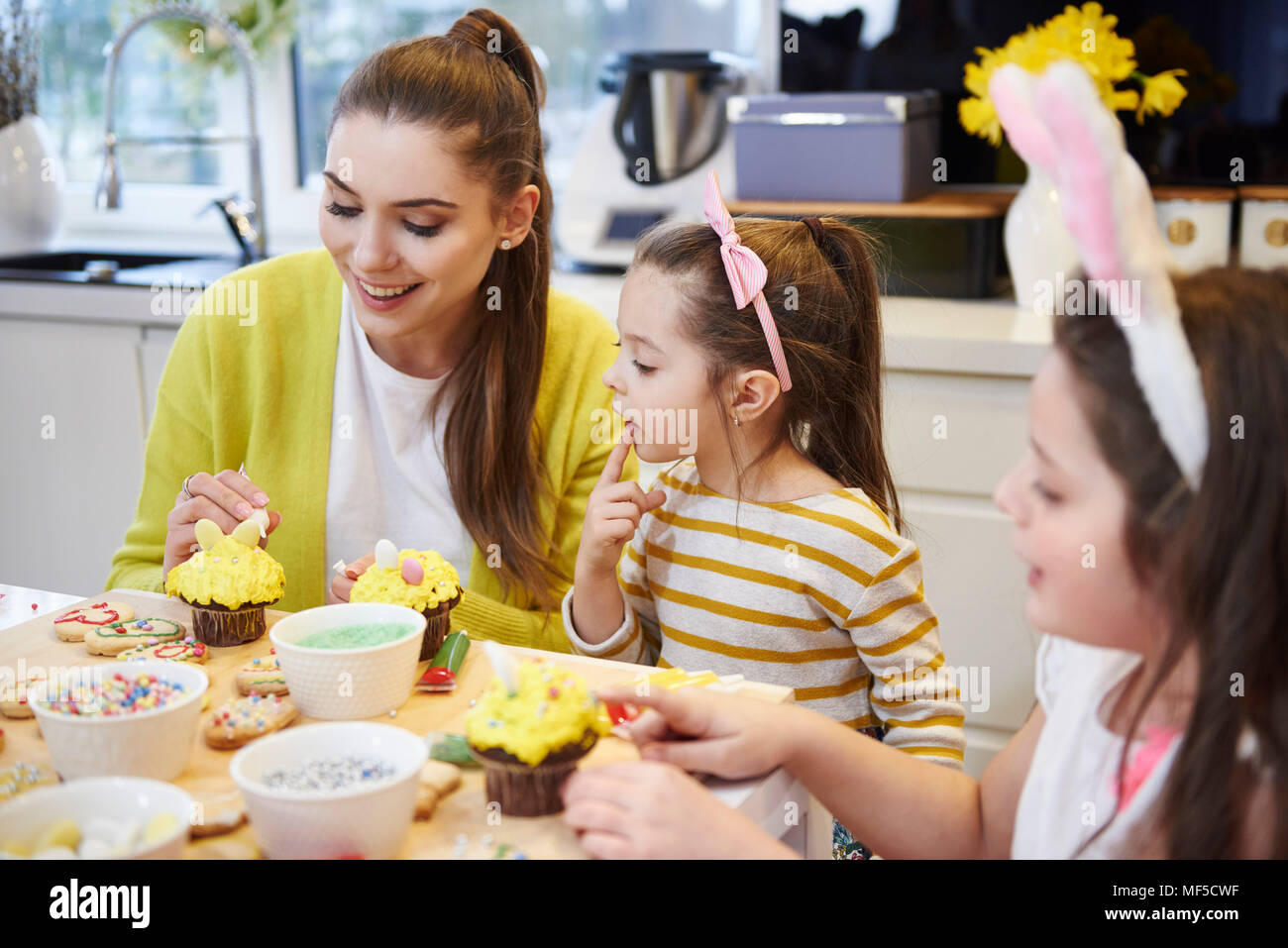Mutter mit Töchtern Dekoration Ostern Kekse und Muffins in der Küche Stockfoto
