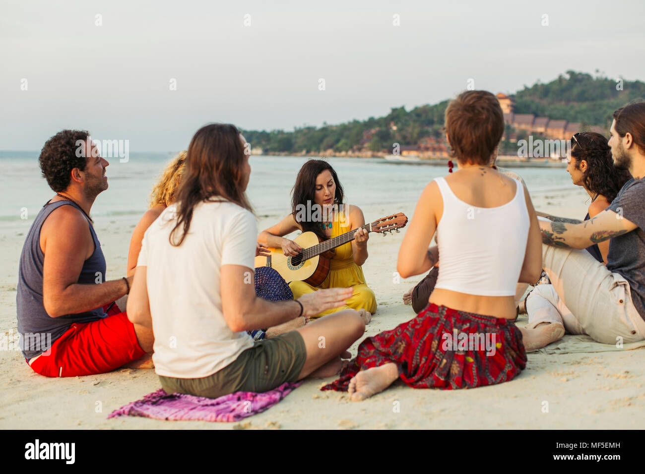 Thailand, Koh Phangan, Gruppe von Menschen sitzen auf einem Strand mit Gitarre Stockfoto