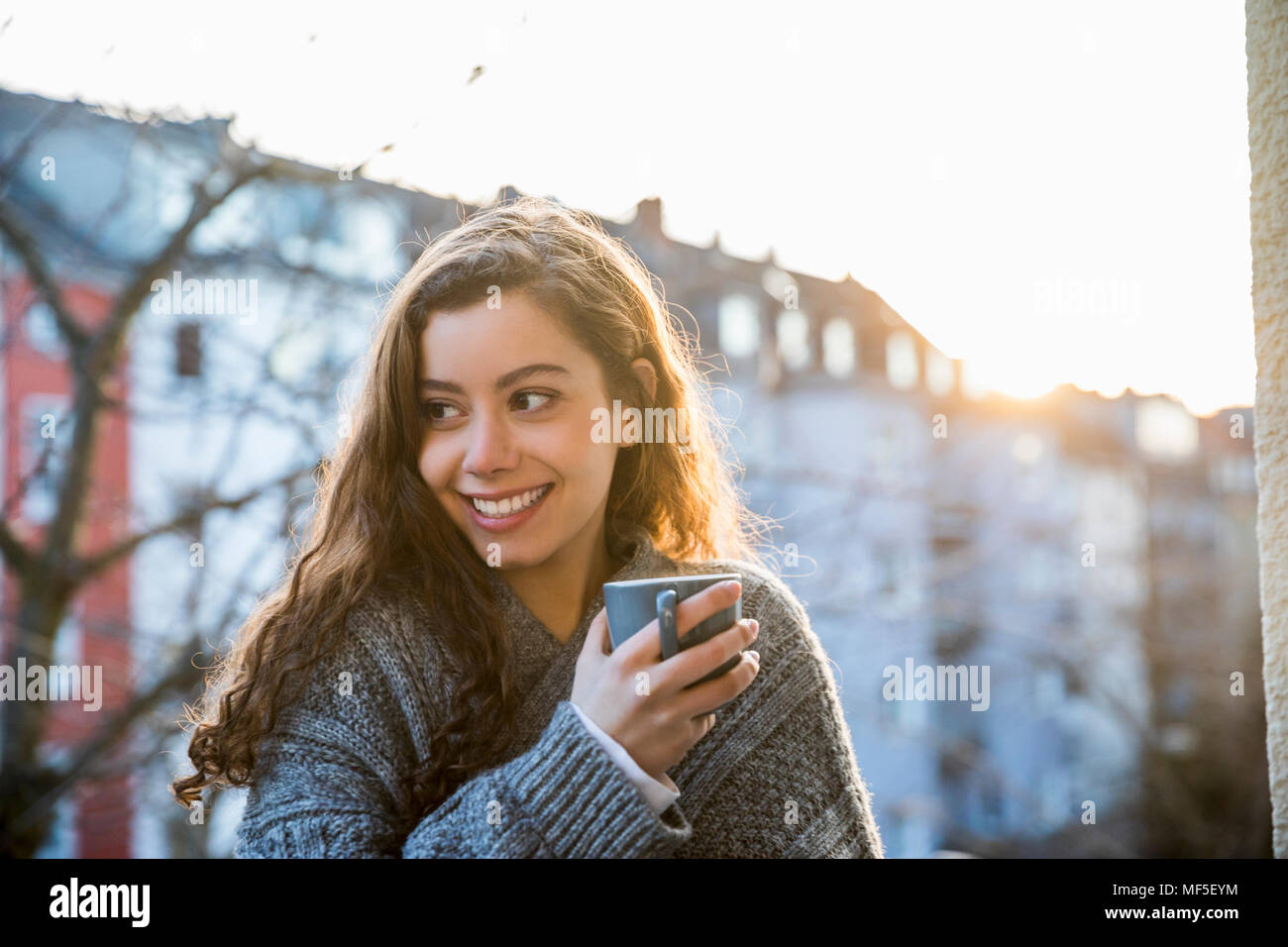 Portrait von Lachen Jugendmädchen mit Kaffeetasse auf dem Balkon in der Dämmerung Stockfoto