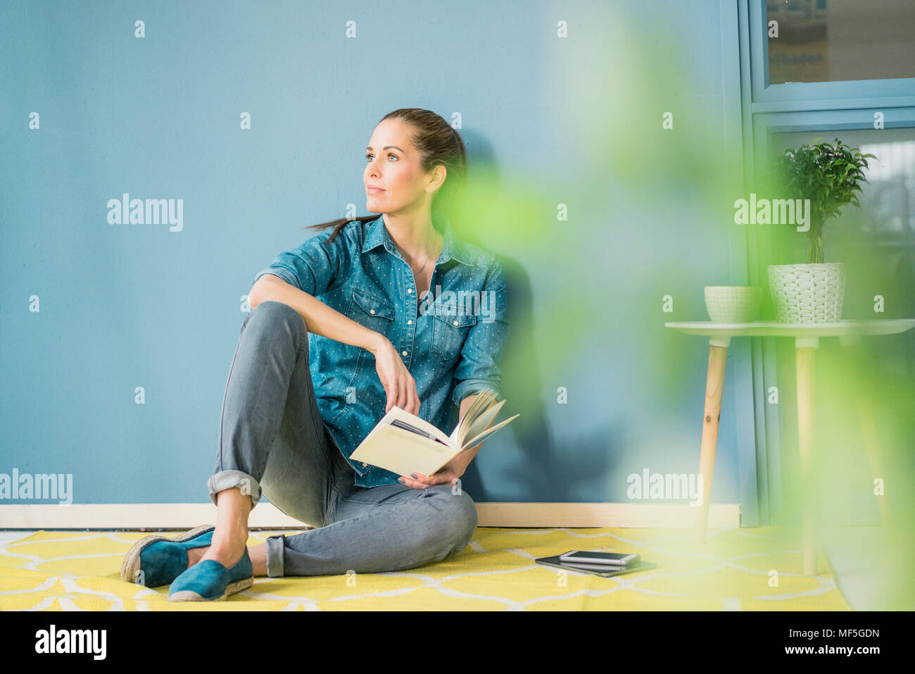 Frau entspannen in Ihrem Haus mit Topfpflanzen, ein Buch lesen Stockfoto