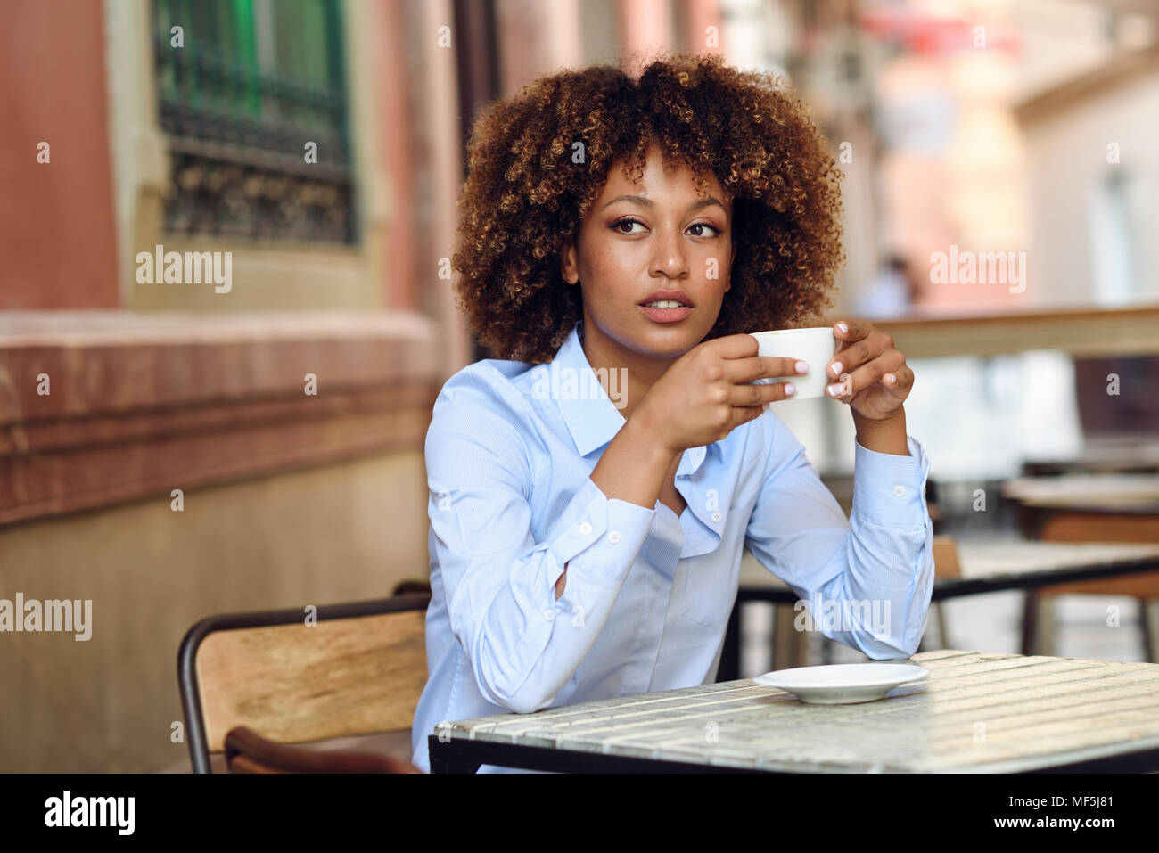 Spanien, Andalusien, Malaga. Schwarze Frau, afro Frisur, in einem Café sitzen. Mädchen mit formalwear eine Pause. Lifestyle Konzept. Stockfoto