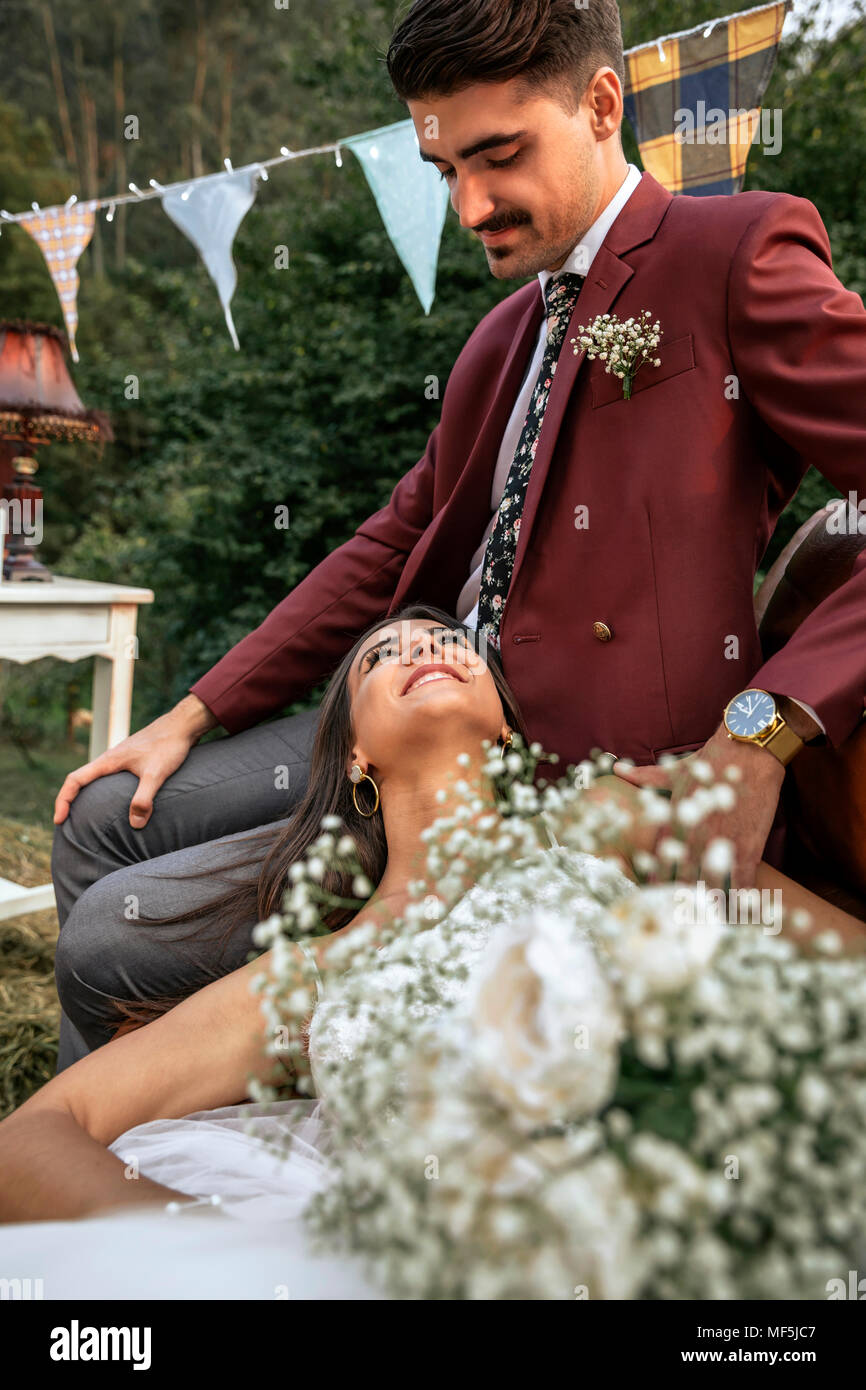 Glückliche Braut lächelnd und Liegen mit Bräutigam in das Feld Stockfoto