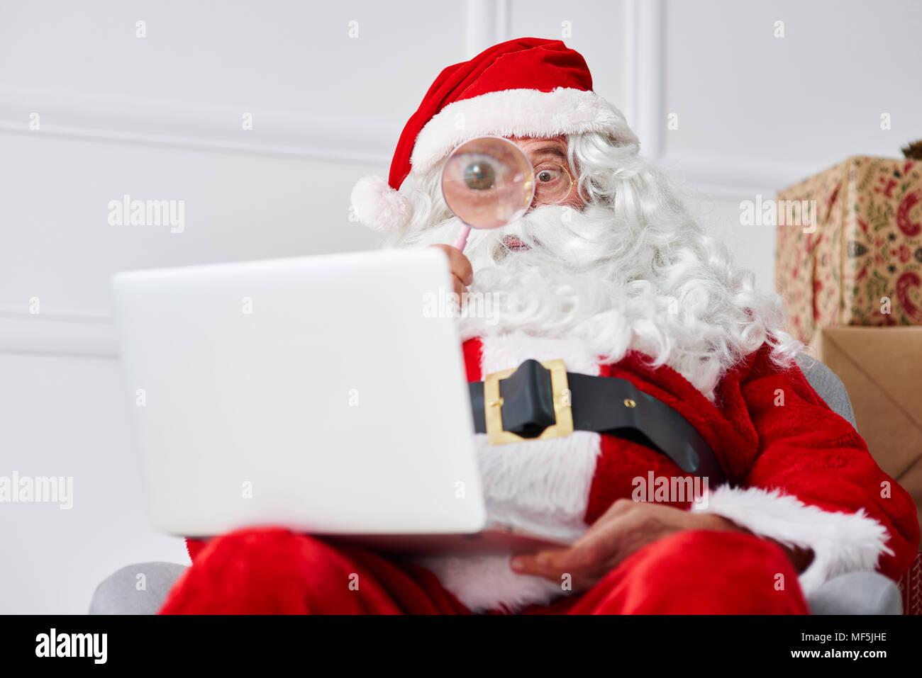 Santa Claus mit Laptop mit Bildschirmlupe Stockfoto
