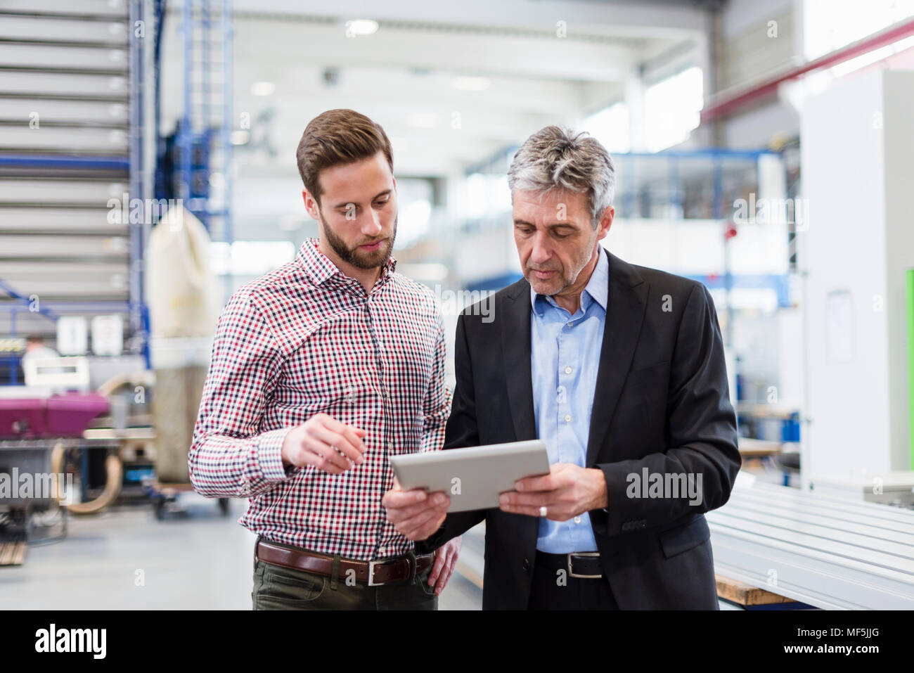 Unternehmer mit Tablette während der Sitzung in der Produktionshalle Stockfoto