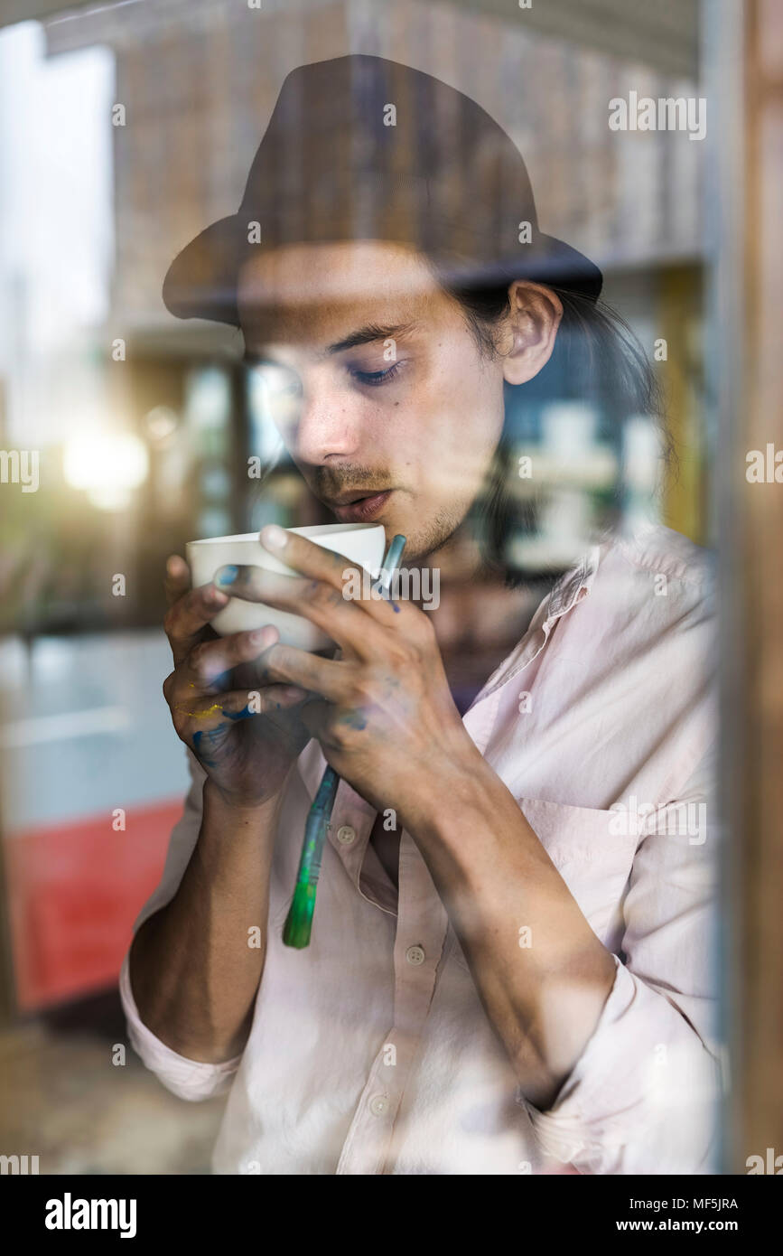 Künstler eine Pause von der Arbeit, lehnte sich gegen Fenster, trinken Kaffee Stockfoto