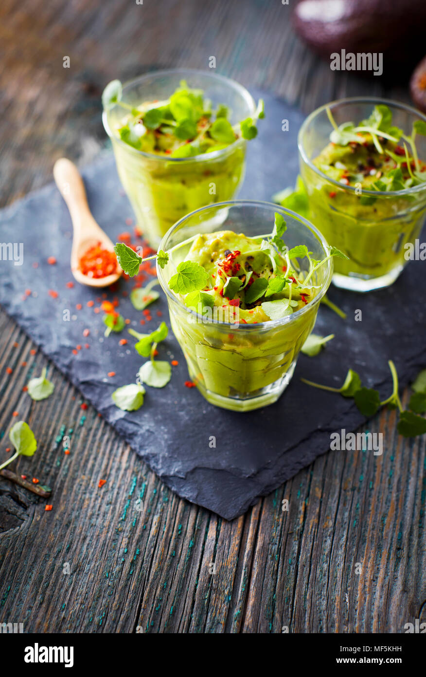 Gläser Avocadocreme mit Chili Flocken, Kresse und Petersilie Stockfoto