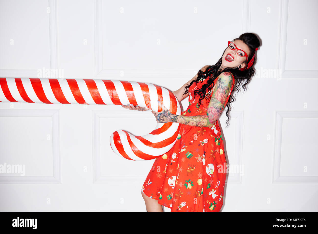 Portrait von tätowierten Frau Spaß mit übergroßen Candy Cane Stockfoto