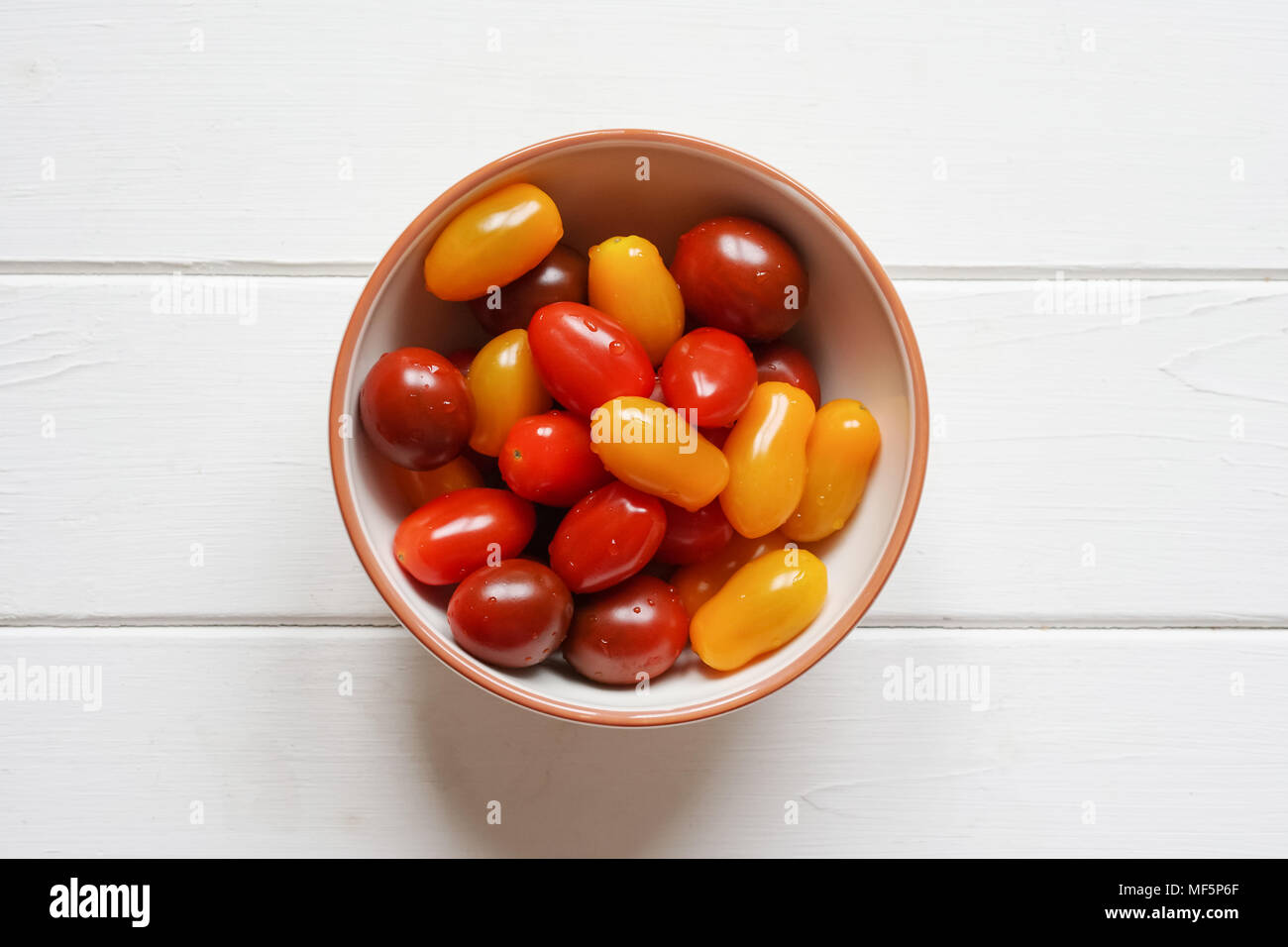 Vielfalt organischer heirloom Tomaten in der Schüssel auf rustikalen weiße Holztisch, Overhead Draufsicht aus direkt über Stockfoto