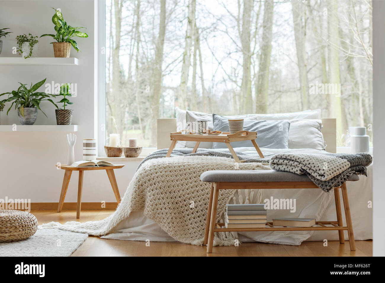 Decke auf Holzbank mit Bücher vor Bett im gemütlichen Schlafzimmer  Einrichtung mit Pflanzen Stockfotografie - Alamy
