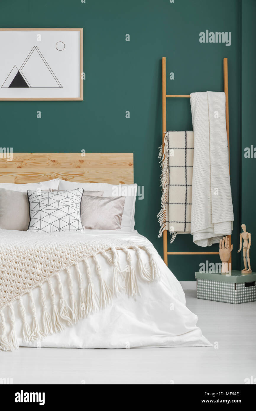 Beige Decken auf dem Bett und Leiter in boho Schlafzimmer Innenraum mit Poster über die grüne Wand Stockfoto