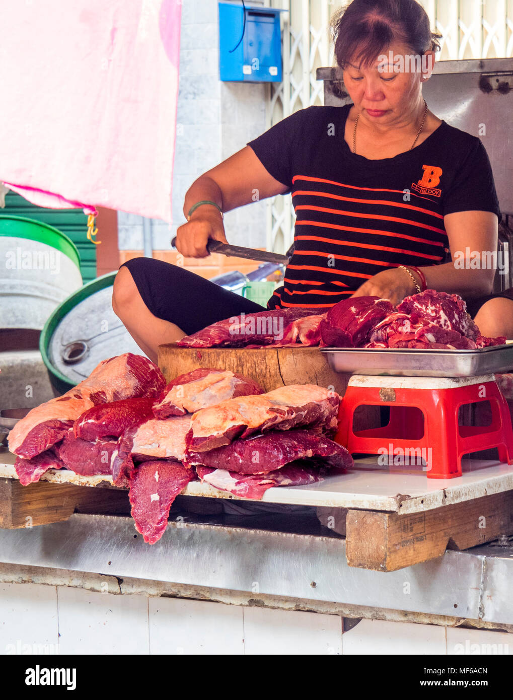 Eine Frau Metzger die Zubereitung von Fleisch in eine Metzgerei in der Tonne stall Dam Straßenmärkte, Ho Chi Minh City, Vietnam. Stockfoto