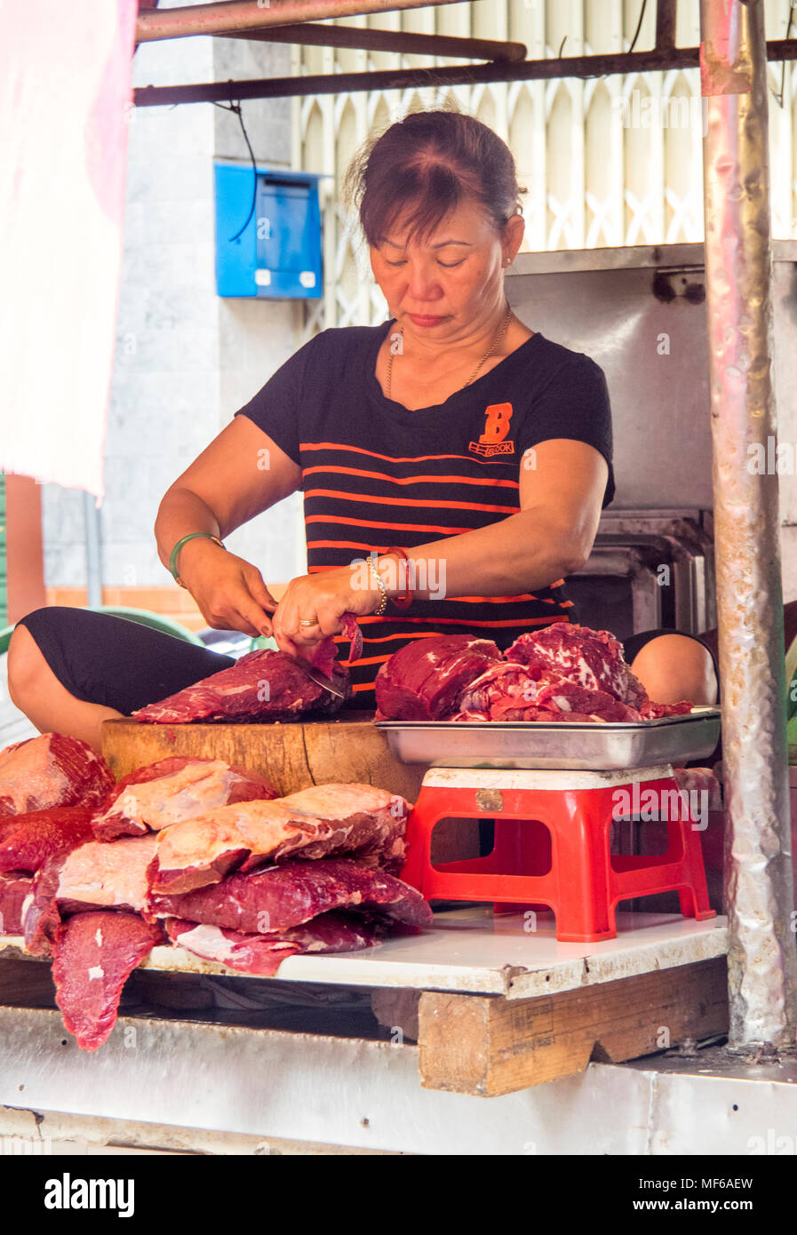 Eine Frau Metzger die Zubereitung von Fleisch in eine Metzgerei in der Tonne stall Dam Straßenmärkte, Ho Chi Minh City, Vietnam. Stockfoto