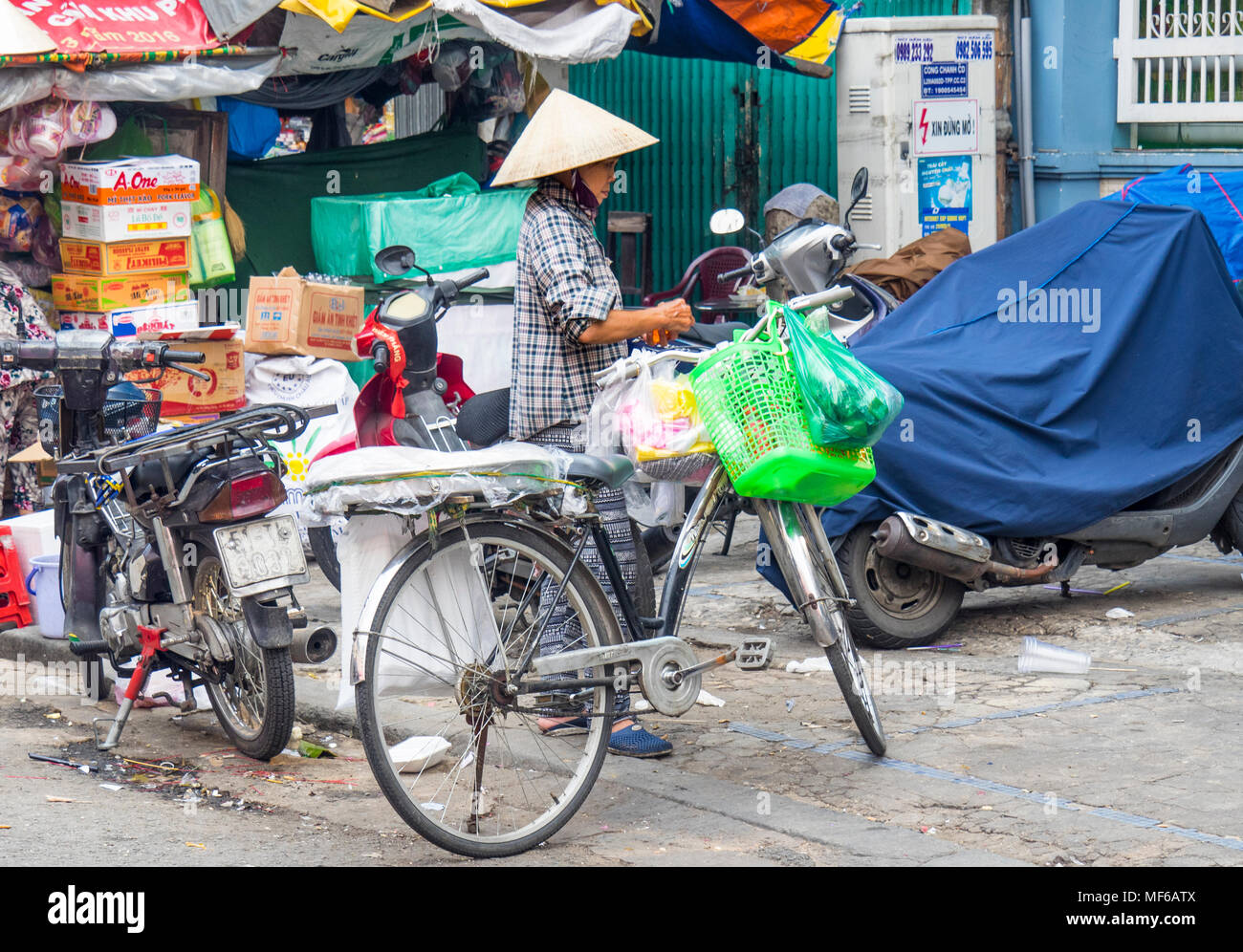 Eine vietnamesische Frau trug eine kegelförmige Hut laden Taschen shopping auf ihr Fahrrad in der Tonne, Dam Straßenmärkte, Ho Chi Minh City, Vietnam. Stockfoto